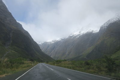 Road leading towards mountains against sky