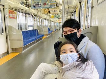 Portrait of young woman using mobile phone while standing in train