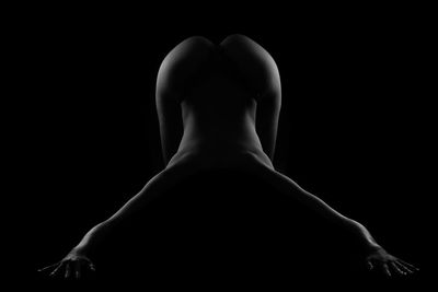 Rear view of silhouette woman against black background