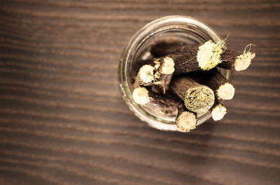 Directly above shot of liquorice roots in container on wooden table