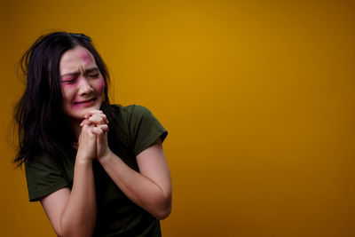 Portrait of beautiful young woman against yellow background