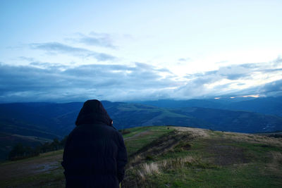 Rear view of man standing on landscape against sky