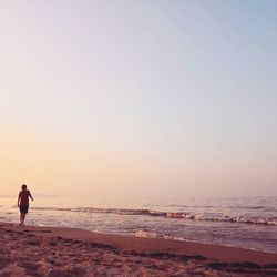 Man on beach against sky during sunset