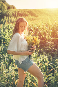 Side view of woman standing amidst farm