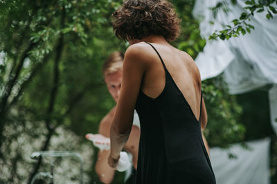 Rear view of woman standing against trees in forest