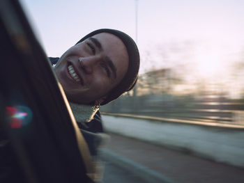 Close-up of smiling man in car against sky