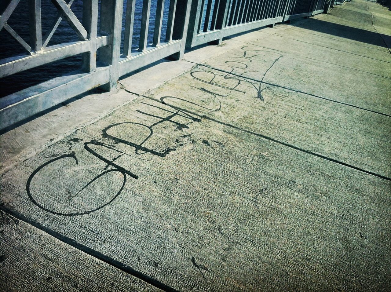 high angle view, metal, pattern, street, sunlight, asphalt, textured, shadow, sidewalk, day, safety, road marking, outdoors, no people, built structure, close-up, transportation, road, metallic, architecture