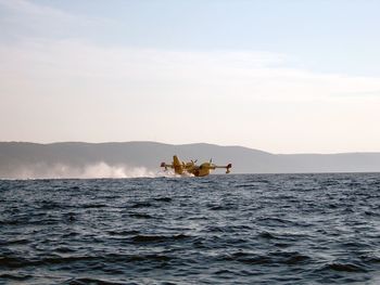 View of airplane landing in sea against sky