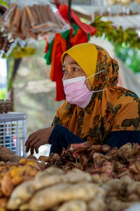 Woman seller wearing face mask at the local ingredients fresh food stall.