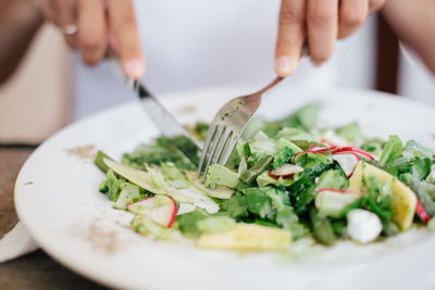 Cropped image of hands eating salad at home