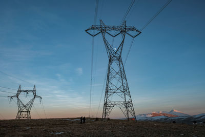 High voltage power lines on mountain against sunset