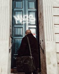 Rear view of woman standing at entrance of building