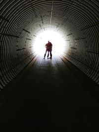 Rear view of silhouette man walking in tunnel