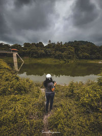 Rear view of man photographing against sky