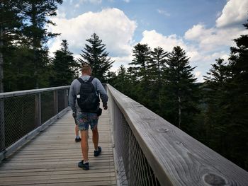 Rear view of man walking on footbridge