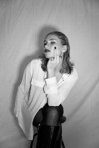 Portrait of young woman drinking water while sitting on bed at home