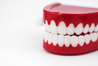 Close-up of artificial red cup on table against white background