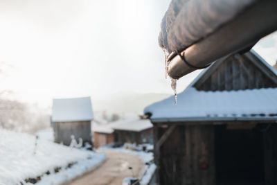 Ice rink hanging from a rooftop of a wooden cabin, old farm house, in winter