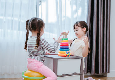 Sisters playing with multi colored toys at home