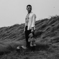 Portrait of boy standing on field against sky