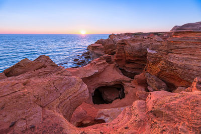 Rock formations in sea against sky during sunset