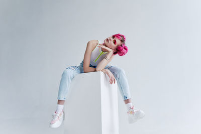 Young woman sitting against white background