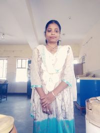 Portrait of young woman standing against wall