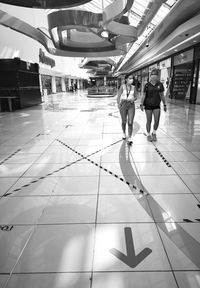 Rear view of people walking on tiled floor