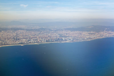 Aerial view of city by sea against sky