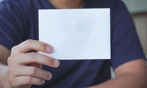 Midsection of man holding paper