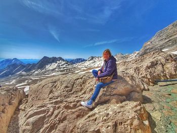 Full length of man sitting on rock against mountains