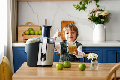 Cute schoolboy makes fresh apple juice for breakfast. vitamins and healthy nutrition for schoolers