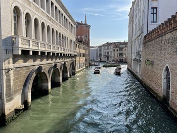 Bridge over canal amidst buildings against sky