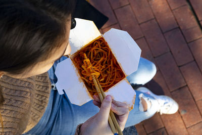 Women's top plan eating chinese noodles with chopsticks.