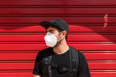 Portrait of young man standing against red wall