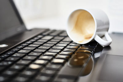 Spill coffee from white cup on computer laptop keyboard.damage to computer due to spilled liquid