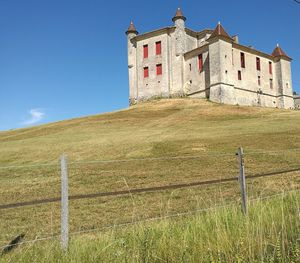 Built structure on field against blue sky