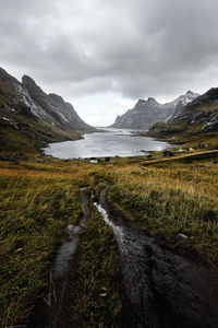 Scenic view of lake amidst mountains against cloudy sky