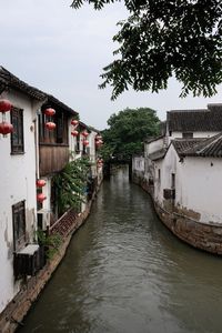 Canal amidst houses against sky