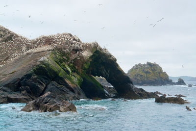 View of rock formation in sea against sky