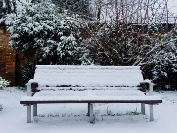 Empty bench in snow covered park during winter