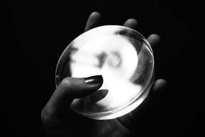 Close-up of woman holding glass against black background
