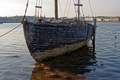 Fishing boats moored at harbor against sky