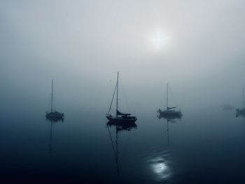 Eerie boats in a still sea against sky