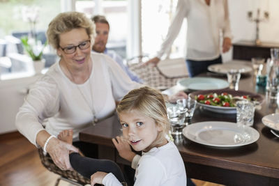 Portrait of girl sitting with family at dining table