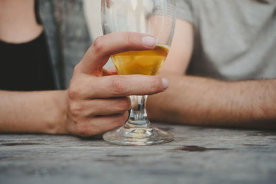 Midsection of man holding beer glass on table