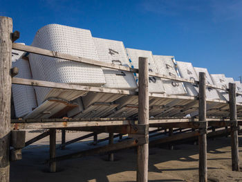 Low angle view of railing on beach against blue sky