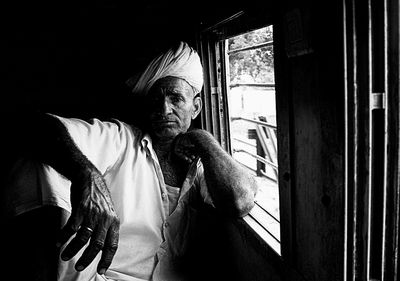 Portrait of man sitting on window
