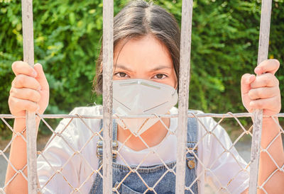 Close-up portrait of woman holding fence