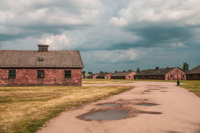 House on field by houses against sky